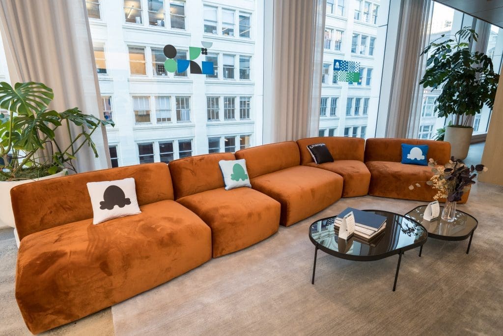 Branded lounge area with Chainguard pillows and floor-to-ceiling Union Square views at Convene San Francisco